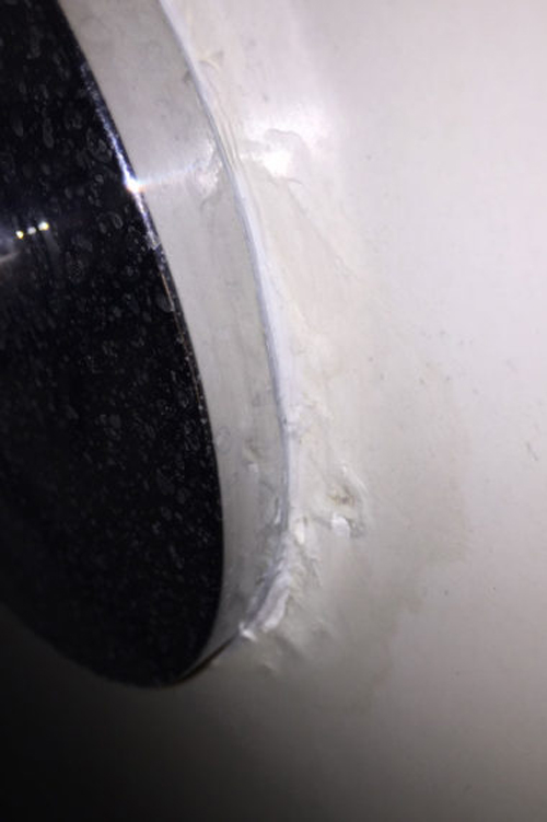 Water gathered below a plaster around a shower's faucet handles, leaving a black mark