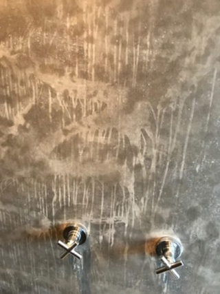 A plaster on a shower wall is completely ruined by water because of bad waterproofing