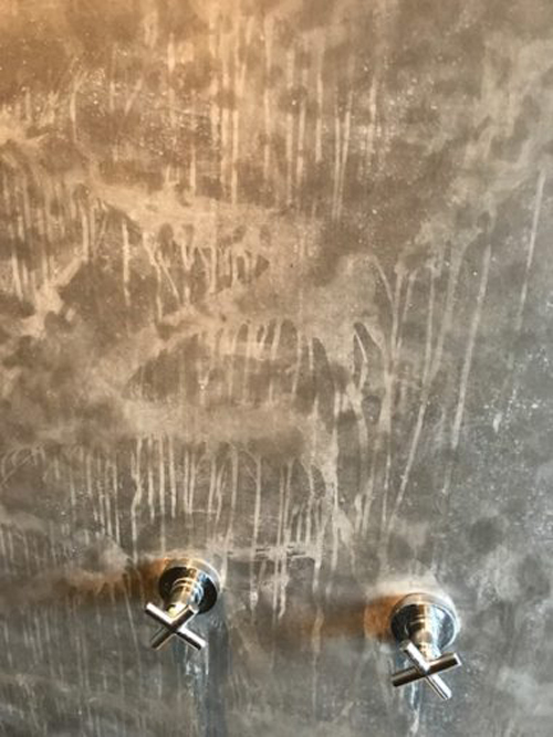 A plaster on a shower wall is completely ruined by water because of bad waterproofing