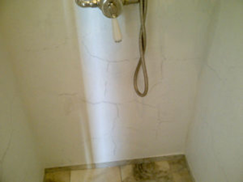 Shower box wall covered with cracks below the handles
